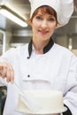 Pretty smiling head chef finishing a cake with icing Royalty Free Stock Photo