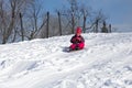 Smiling little girl in her ski suit sliding down a small snow Royalty Free Stock Photo