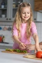 A pretty smiling little girl mistress of the kitchen helps her mother make sandwiches. Woman mom hands supports a