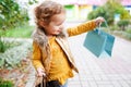 Pretty smiling little girl with shopping bags posing in the park near mall Royalty Free Stock Photo