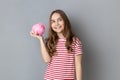 smiling little girl wearing T-shirt holding pig money box in hands, saving money, banking. Royalty Free Stock Photo