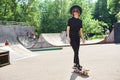 Pretty smiling teenage girl in hat ans sunglasses rides skateboard in skatepark, active and sport lifestyle Royalty Free Stock Photo