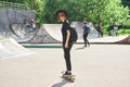 Pretty smiling teenage girl in hat and sunglasses with backpack rides skateboard in skatepark active and sport lifestyle Royalty Free Stock Photo