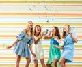 Pretty smiling teenage girls in dresses joyfully running clappers on birthday party Royalty Free Stock Photo