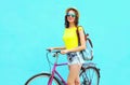 Pretty smiling woman with bicycle over colorful blue