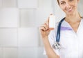 Pretty smiling woman doctor in uniform pointing a medicine bottle Royalty Free Stock Photo