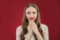 Pretty smiling woman with makeup and manicured nails on her hands on red background Royalty Free Stock Photo