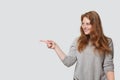 Pretty smiling woman pointing finger at copy space on white studio wall background Royalty Free Stock Photo