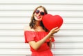 Pretty smiling woman in red dress and sunglasses with air balloons heart shape walking at city over white Royalty Free Stock Photo