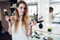 Pretty smiling woman standing with a variety of make-up brushes at beauty studio Royalty Free Stock Photo