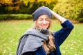 Pretty smiling woman wearing knitting hat and scarf laughing outdoor in the city park in fall season