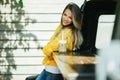 Pretty smiling woman is wearing yellow sweater drinking coffee latte near old retro bus Royalty Free Stock Photo