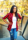 Pretty smiling young african woman wearing a red checkered shirt in sunny autumn Royalty Free Stock Photo