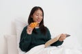 Pretty smiling young asian woman relaxing at home on bed and reading book. Lifestyle concept Royalty Free Stock Photo
