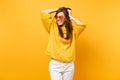 Pretty smiling young woman with closed eyes in fur sweater and heart orange glasses clinging to head isolated on bright Royalty Free Stock Photo