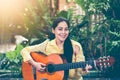 Asian woman playing acoustic guitar with bright sunlight. Vinta Royalty Free Stock Photo