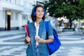 Pretty spanish female student with backpack and earphones