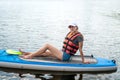 pretty sporty girl learn swim in life vest sitting with paddle on a board in city lake