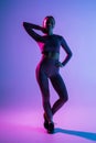 Pretty sporty woman with perfect body standing isolated on purple light background Royalty Free Stock Photo