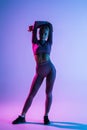 Pretty sporty woman with perfect body standing isolated on purple light background Royalty Free Stock Photo