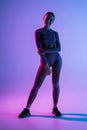 Pretty sporty woman with perfect body standing isolated on purple light background Royalty Free Stock Photo