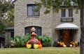 Pretty stone house with awning and fall wreath on door and many pumpkins on porch and big blowup turkey in landscaped front yard