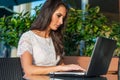 Pretty student girl surfing the internet on her laptop while sitting at outdoor cafe. Young business woman working Royalty Free Stock Photo