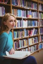 Pretty student sitting on chair holding book in library Royalty Free Stock Photo
