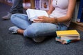 Pretty student sitting on floor reading book in library Royalty Free Stock Photo