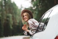 Pretty and style woman traveler sitting in car and looking from window on wild road. Boho girl, wanderlust Royalty Free Stock Photo