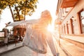 Pretty stylish blonde woman in vintage denim clothes dancing on the street at sunset. Back view Royalty Free Stock Photo