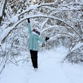 pretty stylish girl walks in winter park among trees covered with snow. Girl is wearing warm jacket Royalty Free Stock Photo