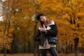 Pretty stylish model of a young woman in fashionable clothes in an elegant hat with a leather handbag posing in the park on an Royalty Free Stock Photo