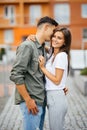 Pretty summer sunny outdoor portrait of young couple while kissing on the street. Royalty Free Stock Photo