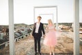 Pretty sunny outdoor portrait of young stylish couple while kissing on the roof with city view Royalty Free Stock Photo