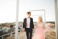 Pretty sunny outdoor portrait of young stylish couple while kissing on the roof with city view Royalty Free Stock Photo