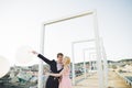 Pretty sunny outdoor portrait of young stylish couple while kissing on the roof with city view Royalty Free Stock Photo