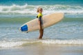 cute surfer girl coming out of the ocean in bikini with her surfboard Royalty Free Stock Photo