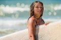 cute surfer girl coming out of the ocean in bikini with her surfboard Royalty Free Stock Photo