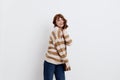 a pretty sweet woman is standing on a light background in a striped sweater and a bag on her shoulder, standing straight Royalty Free Stock Photo