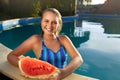 Pretty tanned slim young woman holds slice red watermelon over blue pool, relaxing on tropical island in resort, eating Royalty Free Stock Photo