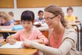 Pretty teacher helping pupil in classroom