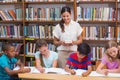 Pretty teacher helping pupils in library