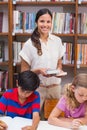 Pretty teacher helping pupils in library