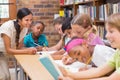 Pretty teacher helping pupils in library