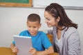 Pretty teacher and pupil using tablet at his desk Royalty Free Stock Photo