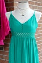 Pretty teal blue dress on mannequin with small necklaces to dress it up