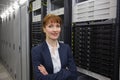 Pretty technician smiling at camera beside server tower Royalty Free Stock Photo