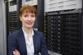 Pretty technician smiling at camera beside server tower Royalty Free Stock Photo