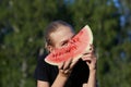 Pretty teen girl holding slice of watermelon in front of face on green nature background Royalty Free Stock Photo